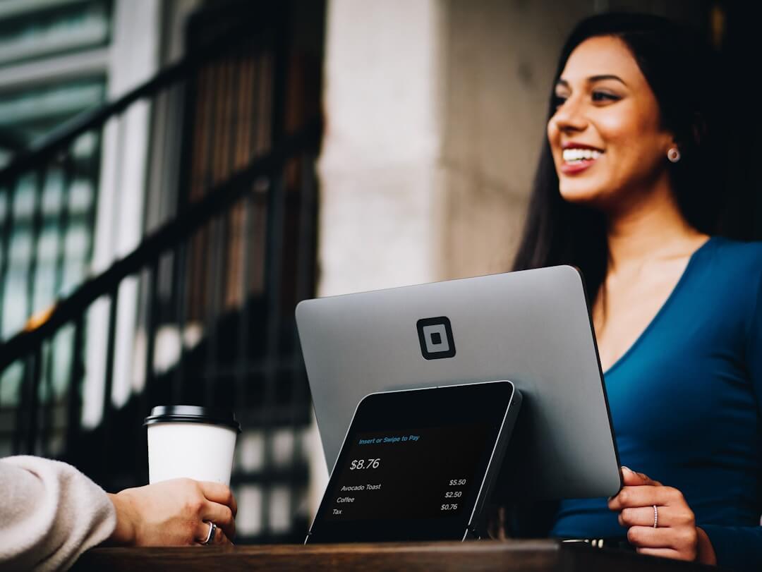 A smiling woman using a laptop, representing improved collaboration in proposal management workflows.